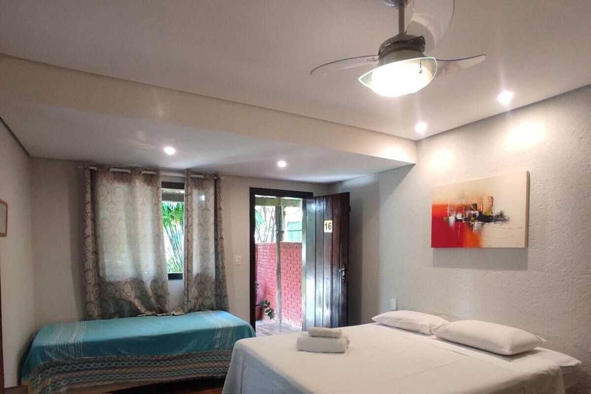 A bedroom with two beds, a ceiling fan, and a door leading outside.