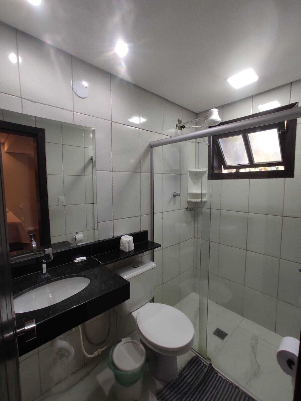 A modern bathroom with a glass-enclosed shower, a white toilet, and a black sink.