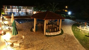 An outdoor pool area with stone flooring, a gazebo, and outdoor seating. - Pousada Banana Cipó (Santana do Riacho)