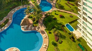 A resort with multiple swimming pools, a well-maintained lawn, and a large building. - Ph Toshi (Puerto Vallarta)
