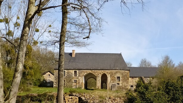 A stone building with a large arched entrance, surrounded by trees and grass. - Chambres d'hôtes La Chaussée d'Olivet (Olivet)