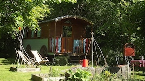 A wooden cabin with a porch, surrounded by lush greenery and a garden with plants and a swing set. - Chambres d'hôtes La Chaussée d'Olivet (Olivet)