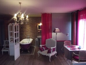 A bathroom with a bathtub, a mirror, a sink, and a chair. - Chambres d'hôtes La Chaussée d'Olivet (Olivet)