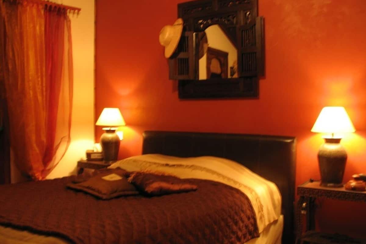 A bedroom with a bed, two bedside lamps, a nightstand, and a wall-mounted picture frame.