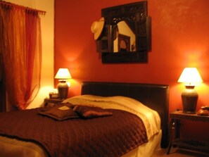 A bedroom with a bed, two bedside lamps, a nightstand, and a wall-mounted picture frame. - Chambres d'hôtes La Chaussée d'Olivet (Olivet)