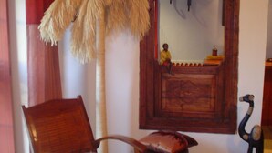 A room with a wooden chair, a small round table, a decorative ostrich sculpture, and a mirror with a wooden frame. - Chambres d'hôtes La Chaussée d'Olivet (Olivet)