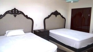 A hotel room with two single beds, each with a wooden headboard and white bedding. There is a small bedside table with a lamp between the beds. - Unlimited Luxury Villa  LOS TULES (Puerto Vallarta)