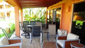 An outdoor patio area with a table and chairs, surrounded by plants and a building in the background. - Unlimited Luxury Villa  LOS TULES (Puerto Vallarta)