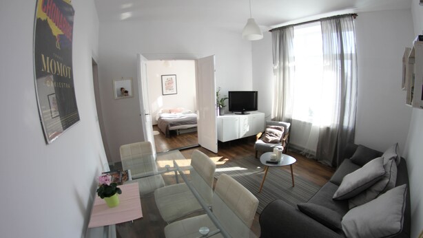 Un salon moderne avec un canapé, un téléviseur et un coin repas comprenant des chaises et une table.
