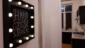 Un couloir avec un grand miroir à cadre noir, doté de lumières, et un tableau noir sur lequel est écrit « HELLO GZESC HOLAS ».
