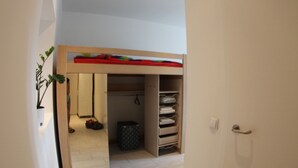 Un intérieur moderne avec un lit superposé, un couloir menant à une autre pièce et une porte dotée d’une poignée.