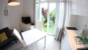 Une cuisine moderne avec un plan de travail blanc, une table à manger et une grande fenêtre agrémentée de rideaux.
