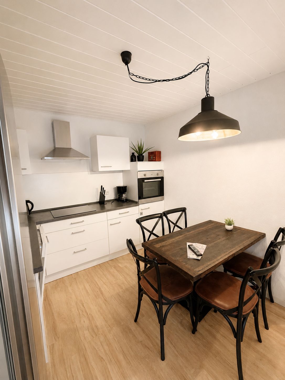 A modern kitchen with white cabinets, a wooden dining table, and black chairs.
