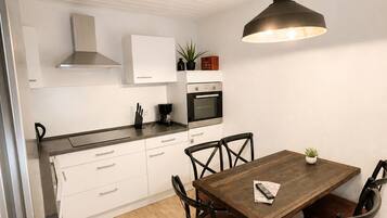 A modern kitchen with white cabinets, a wooden dining table, and black chairs.