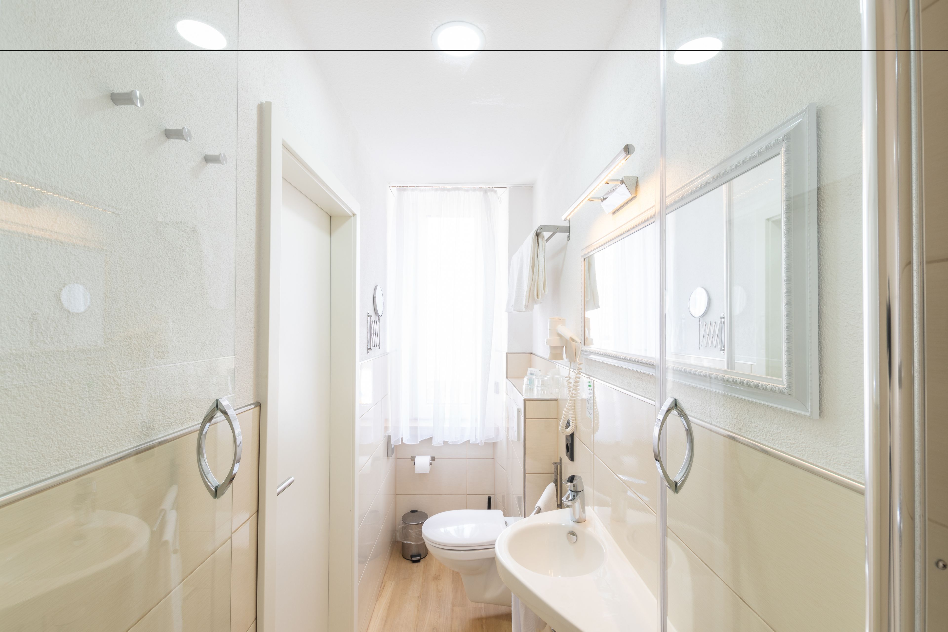 A modern bathroom with a glass shower enclosure, a toilet, and a sink with a mirror above it.