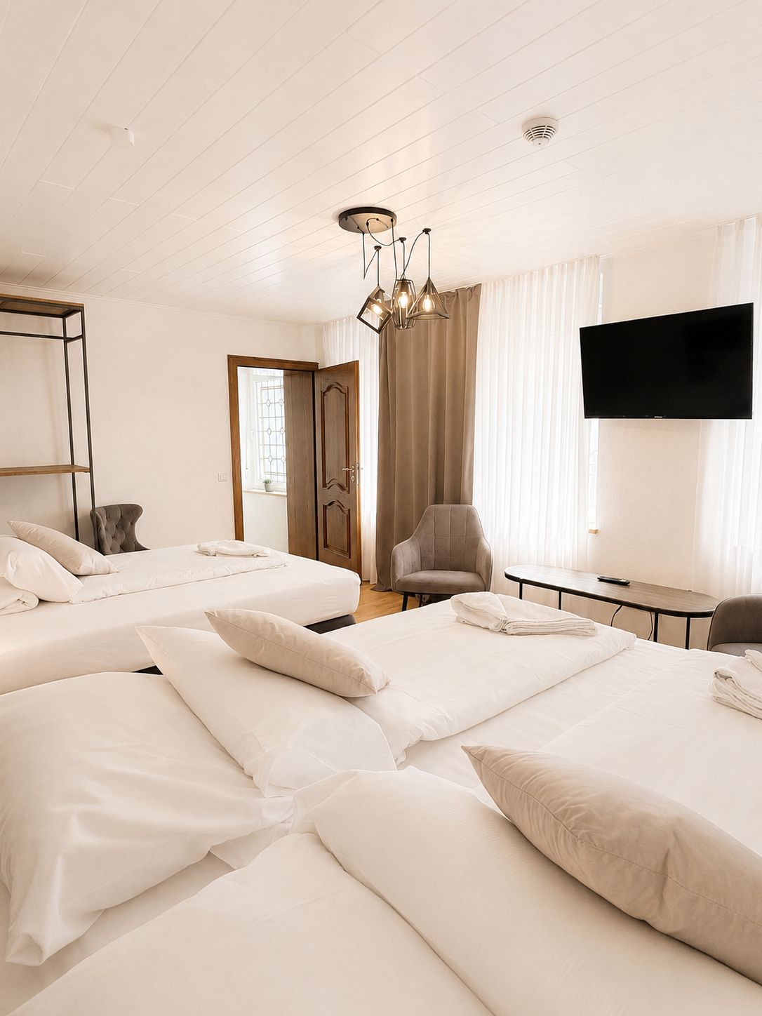 Habitación de hotel con dos camas, un escritorio, una silla, un televisor y una ventana con cortinas.