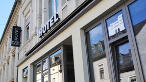 A hotel facade with large windows, a sign reading "HOTEL PORTA NIGRA," and a reflection of a building in the windows. - Hotel Porta Nigra (Trier)
