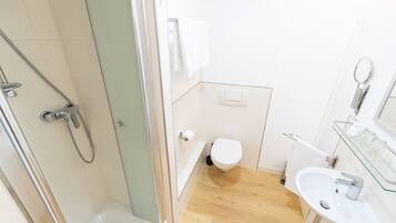 A modern bathroom with a glass-enclosed shower, a white toilet, a sink with a glass shelf, and a mirror.