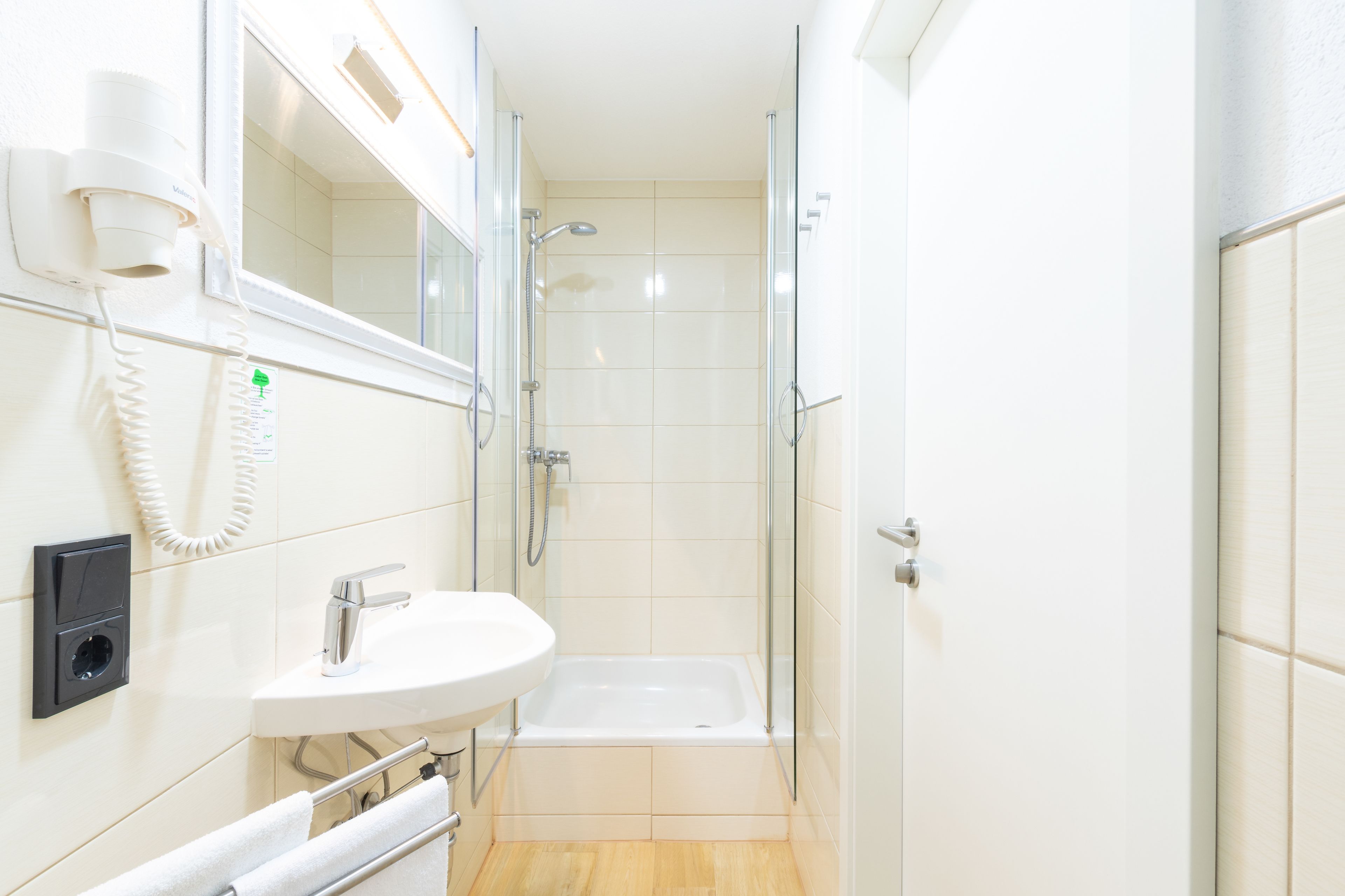 A modern bathroom with a glass shower enclosure, a white sink, and a built-in telephone.