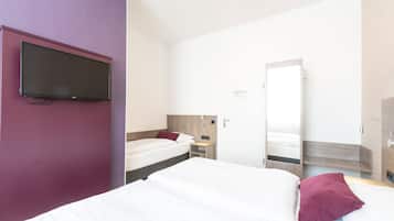 Ein Hotelzimmer mit einem großen Bett, einem kleineren Bett, einem an der Wand befestigten Fernseher, einem Nachttisch und einem Spiegel.