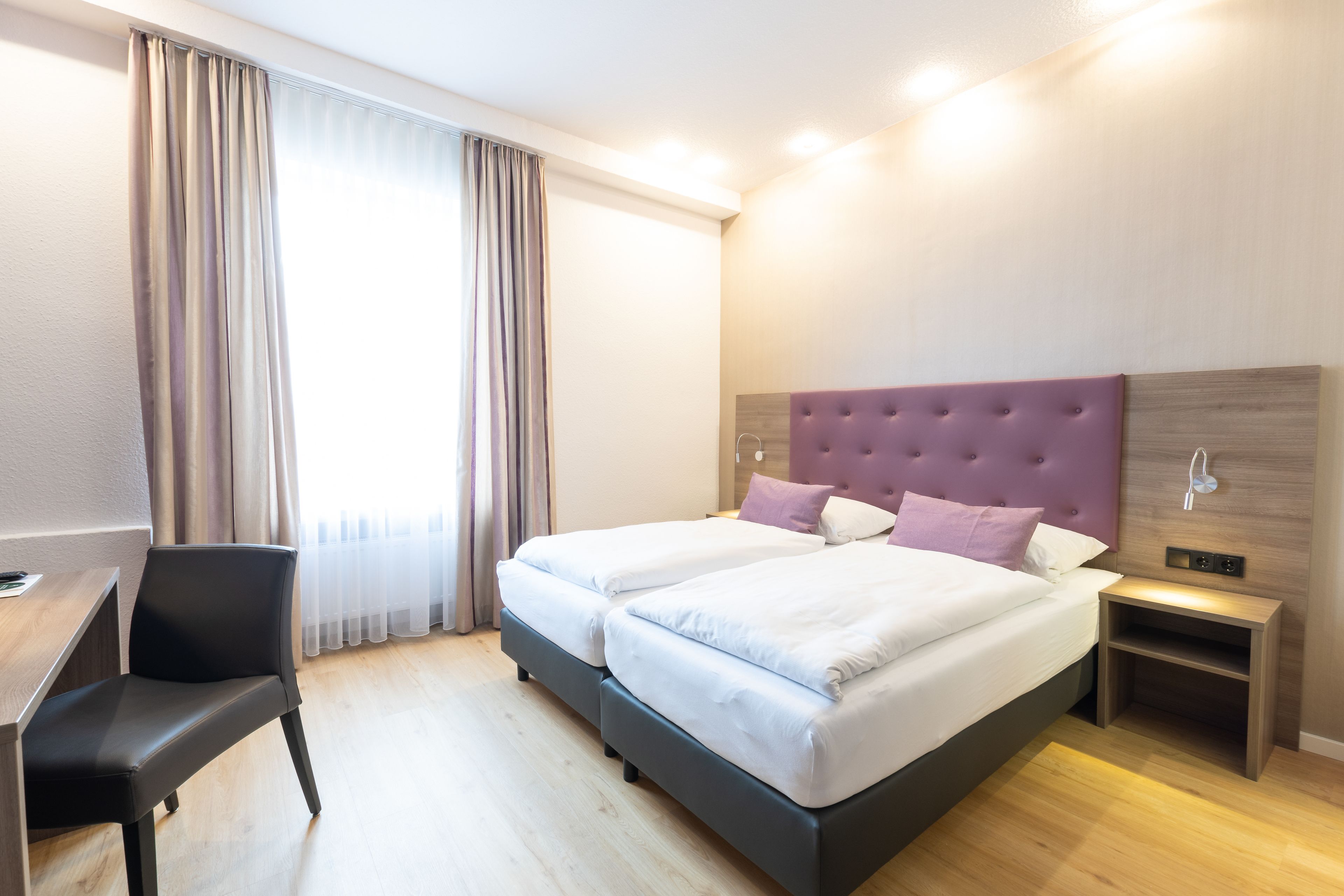 Een moderne hotelkamer met een groot bed, een bureau en een stoel.