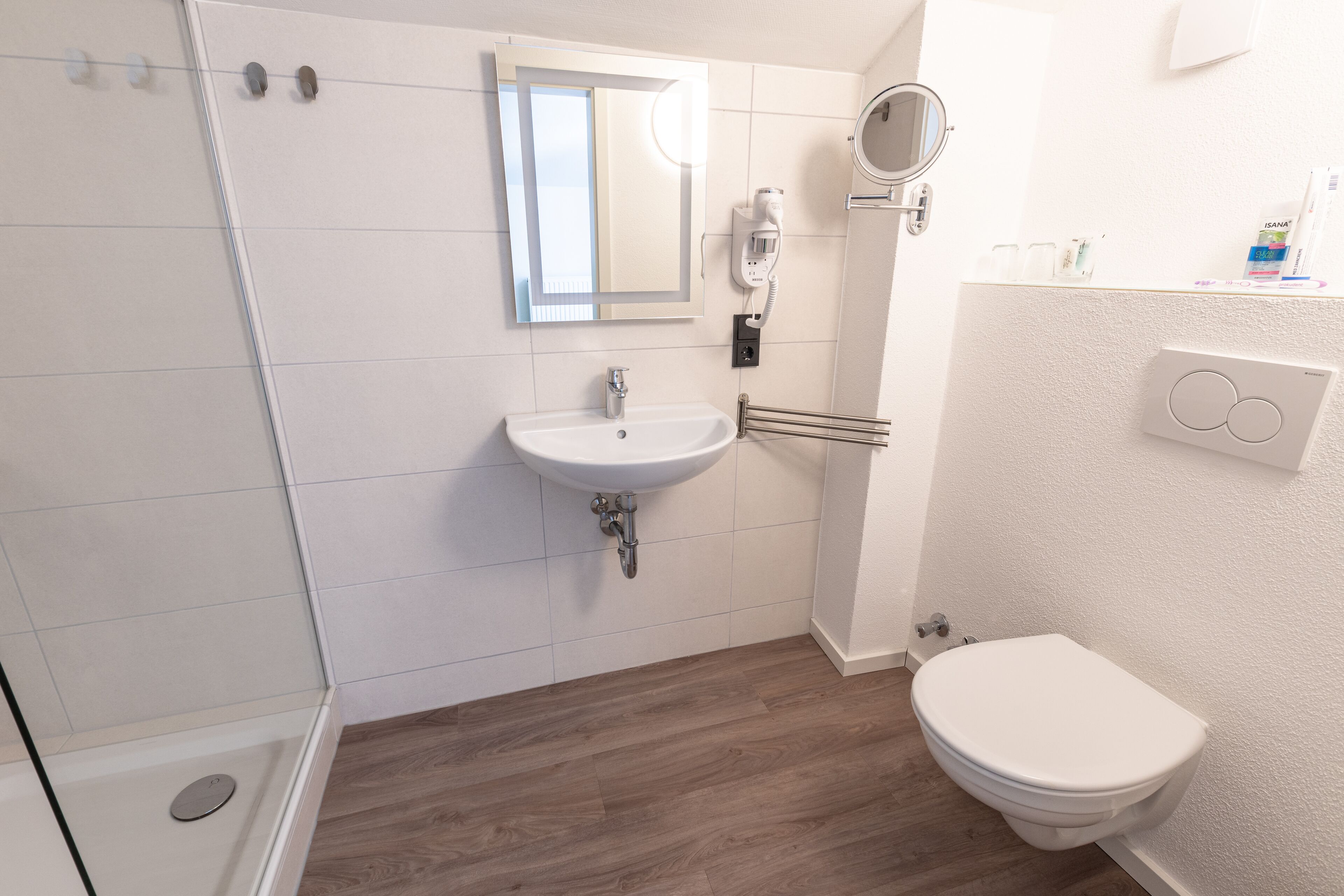 A bathroom with a white sink, mirror, and toilet.
