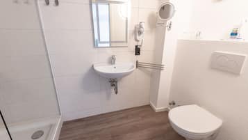 A bathroom with a white sink, mirror, and toilet.