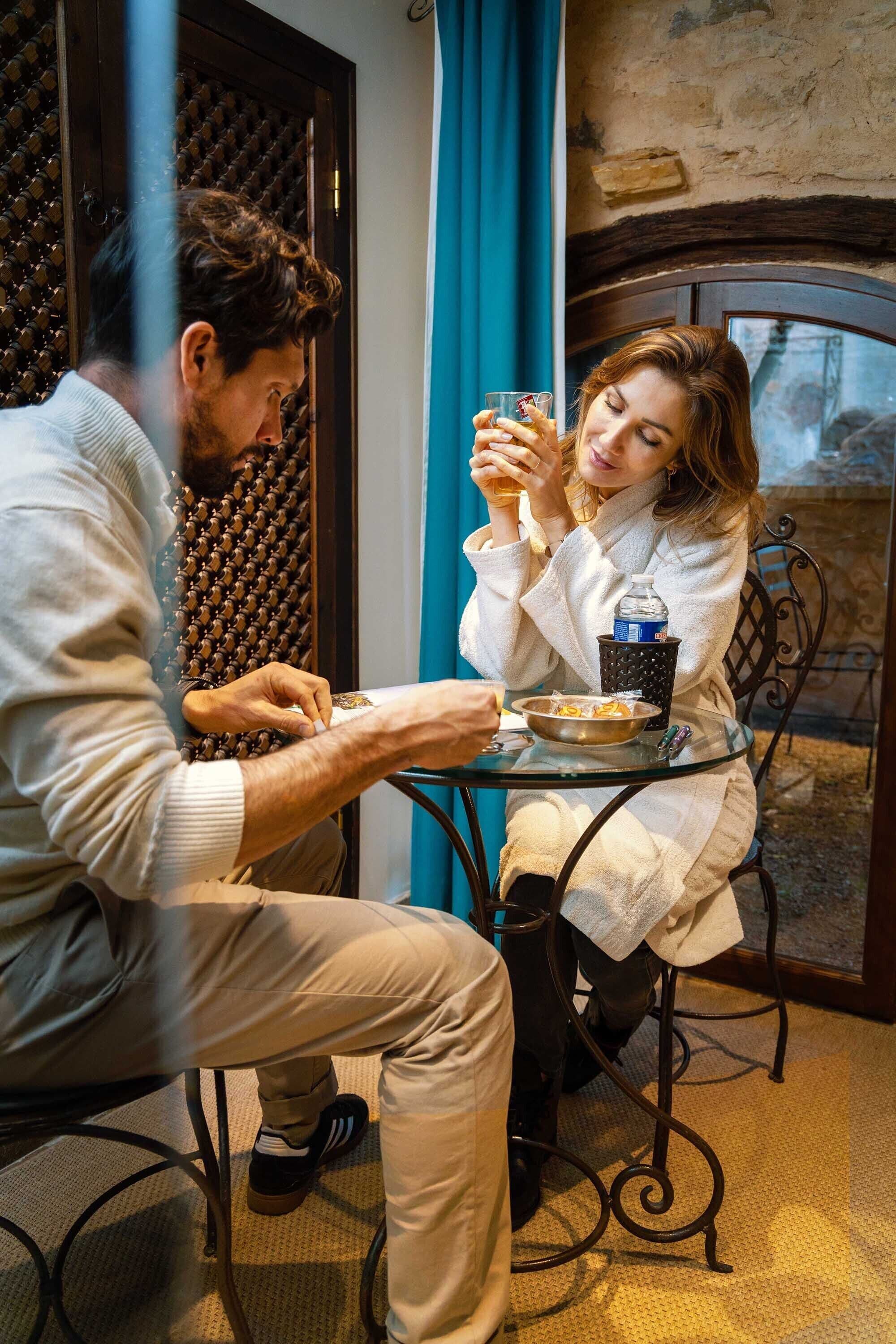A man and a woman sitting at a table with a glass of drink, a bowl of food, and a bottle of water.