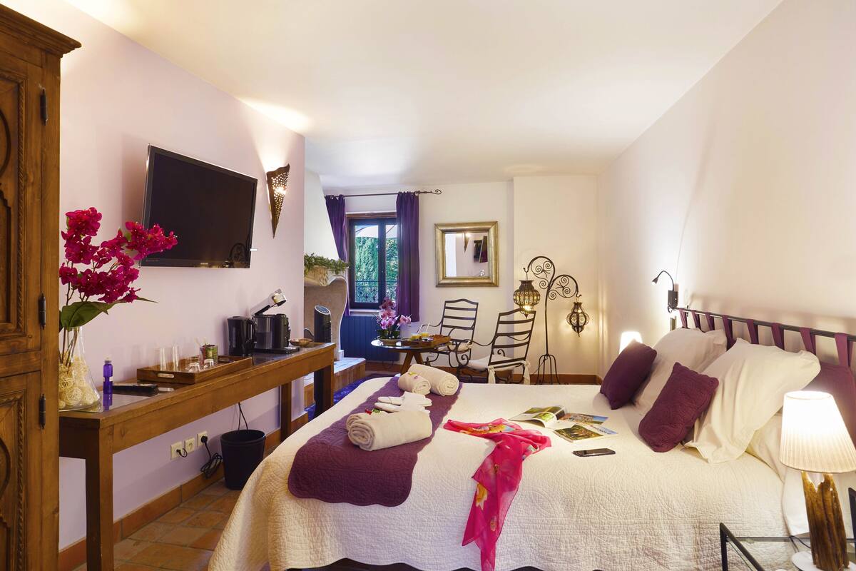 A hotel room with a bed, a desk, a TV, and a window with curtains.