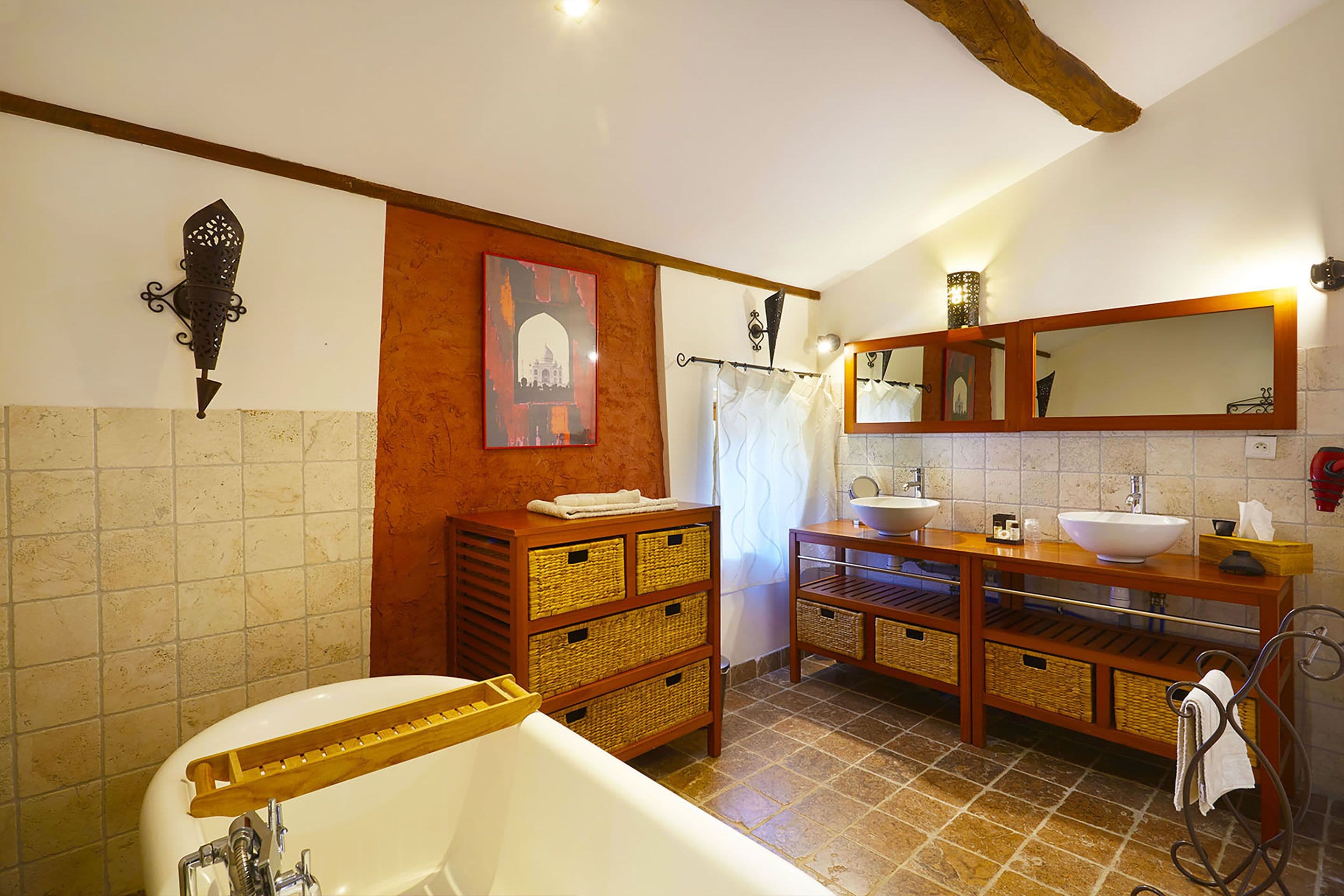 Ein Badezimmer mit einer Badewanne, zwei Waschbecken, Korbwannen, einem Handtuchhalter und einem Spiegel.