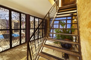 Una escalera de caracol con barandillas metálicas decoradas y vistas a una piscina exterior.