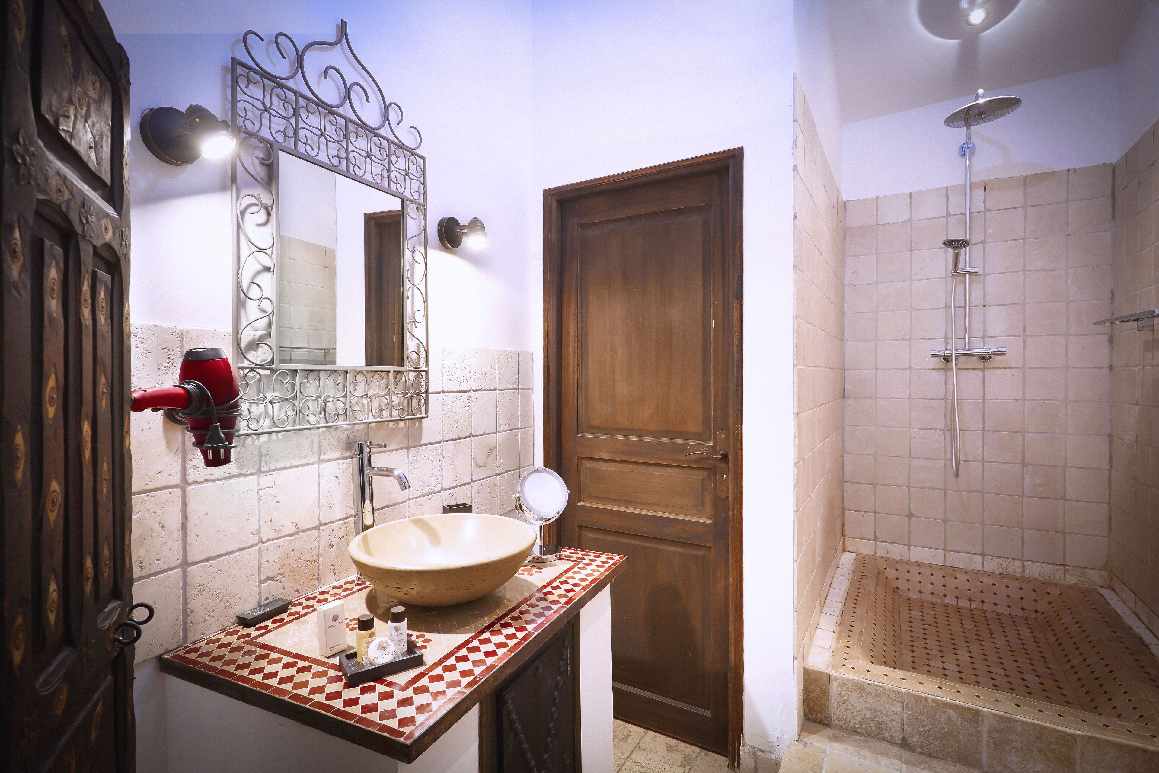 Un baño con un lavamanos grande, un espejo, una ducha y una puerta de madera.