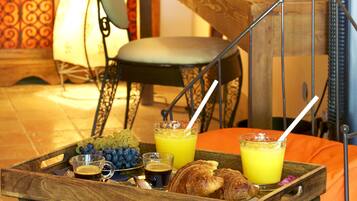 Ein Frühstücksbrett mit Croissants, Trauben und Orangensaft auf einem Tisch mit Metallgestell.