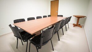 Une salle de conférence avec une longue table en bois, des chaises noires et une petite table en bois.