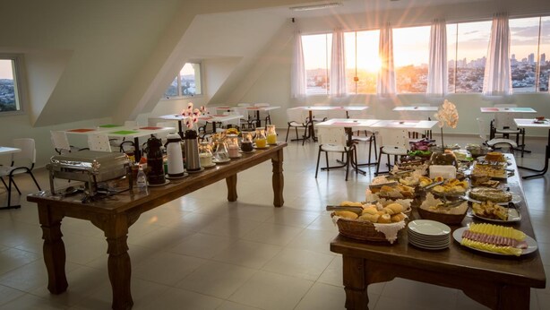 Une pièce spacieuse avec une longue table dressée pour un buffet, proposant divers plats et une machine à café.