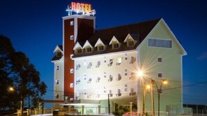 Un hôtel à étages, avec une enseigne « HÔTEL » bien visible et une façade bien éclairée.