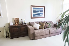 A living room with a brown sofa, a wooden cabinet, and a framed landscape painting on the wall.