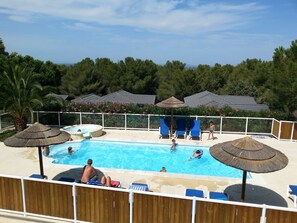 A pool area with lounge chairs, umbrellas, and a view of the surrounding forest.