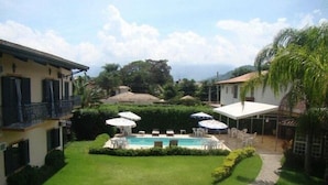 A pool area with umbrellas, chairs, and a clear view of the surrounding landscape. - Pousada Villa Harmonia (Paraty)