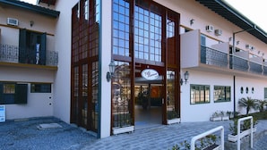 A two-story building with a large glass entrance, a sign reading "Villa Harmonia," and a balcony with a railing. - Pousada Villa Harmonia (Paraty)