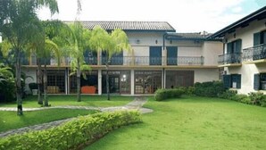 A two-story building with a covered patio area, a well-maintained lawn, and a small garden with a curved pathway. - Pousada Villa Harmonia (Paraty)