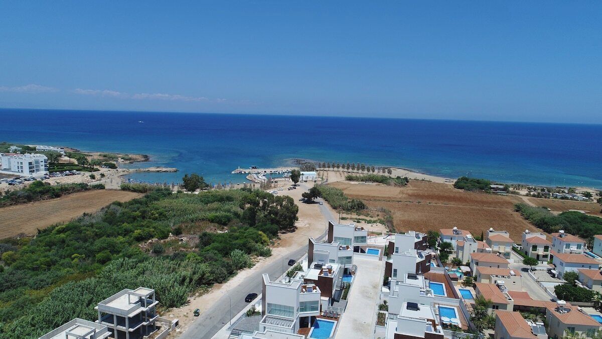 A coastal resort with modern villas, a beach, and a clear view of the sea.
