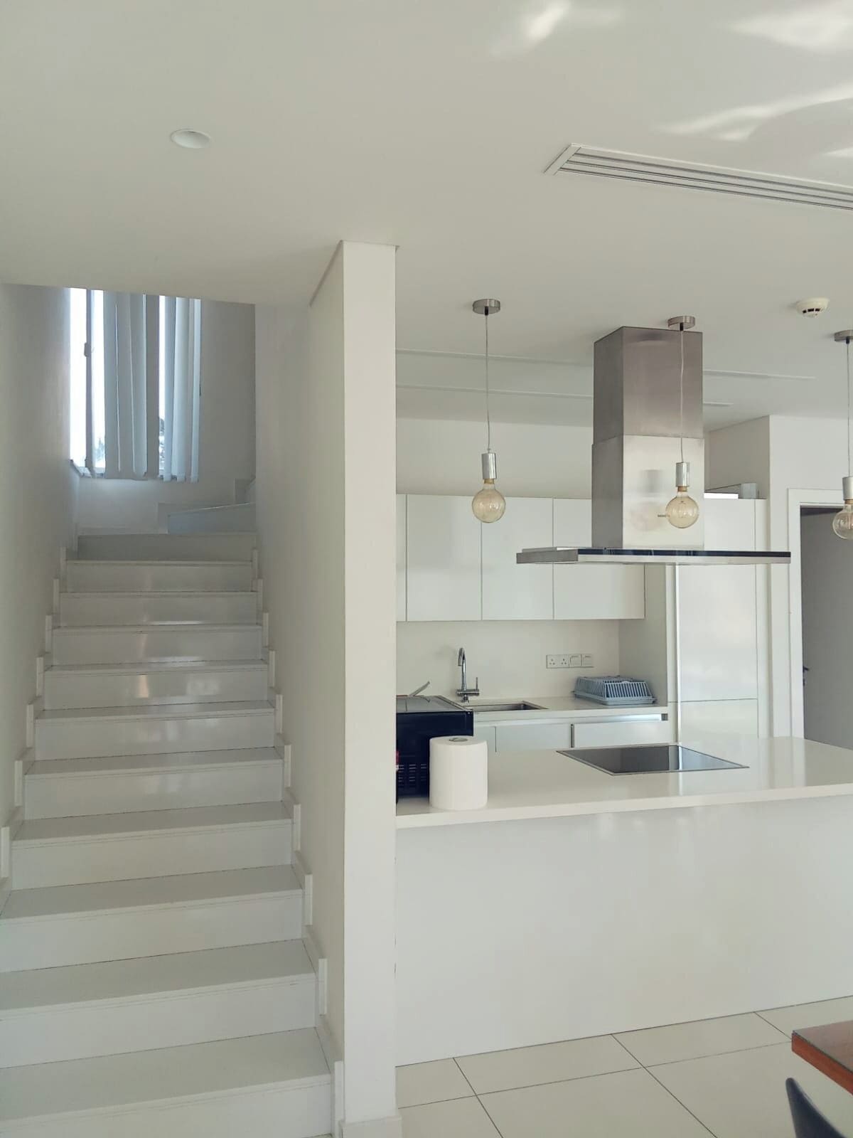 Una cocina moderna con una isla central, electrodomésticos de acero inoxidable e iluminación colgante.