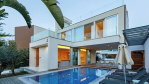 A modern two-story house with a swimming pool, outdoor seating, and a covered patio area. - Sunrise Seaview Villas (Paralimni)