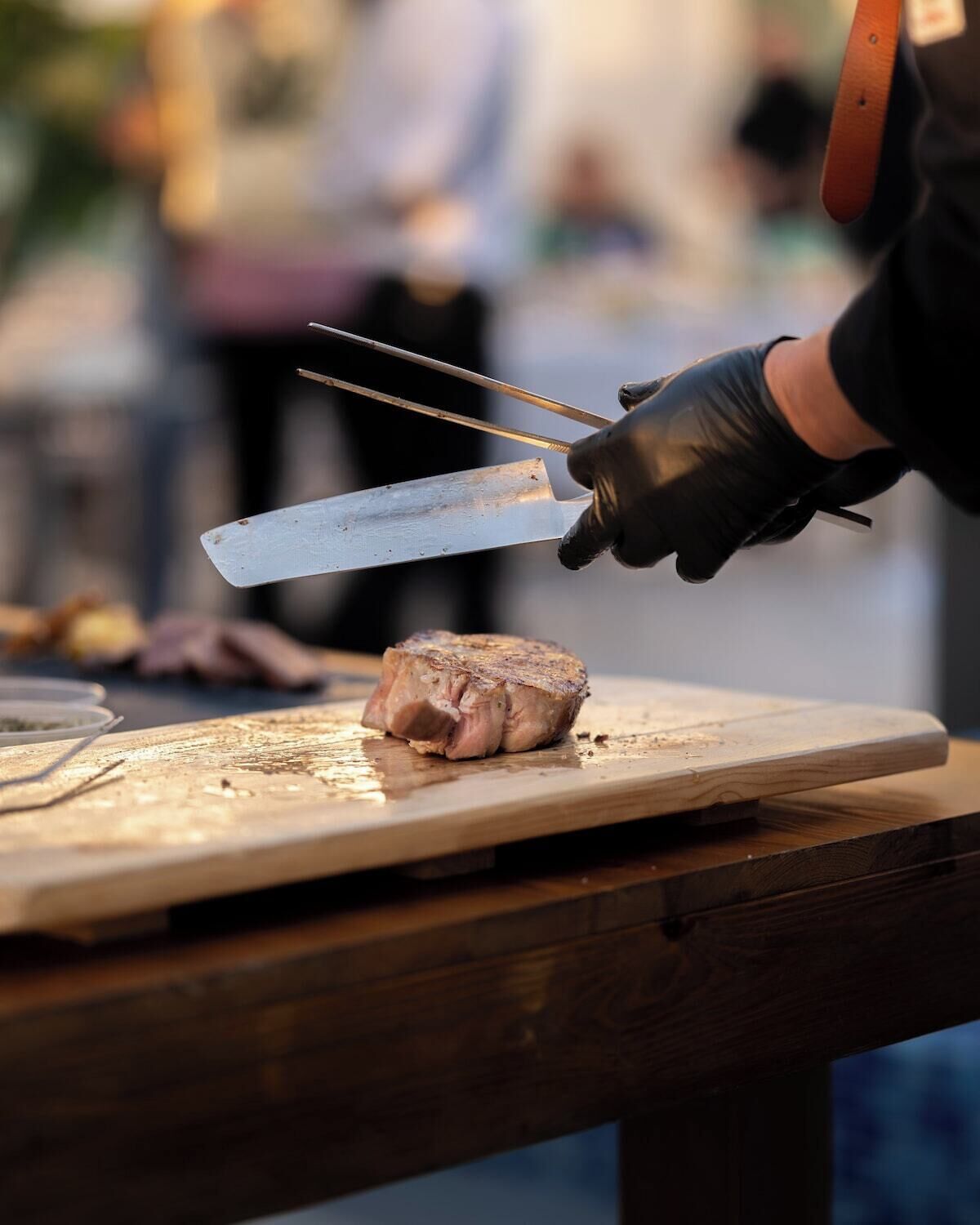 A person using a knife to cut meat on a wooden cutting board.