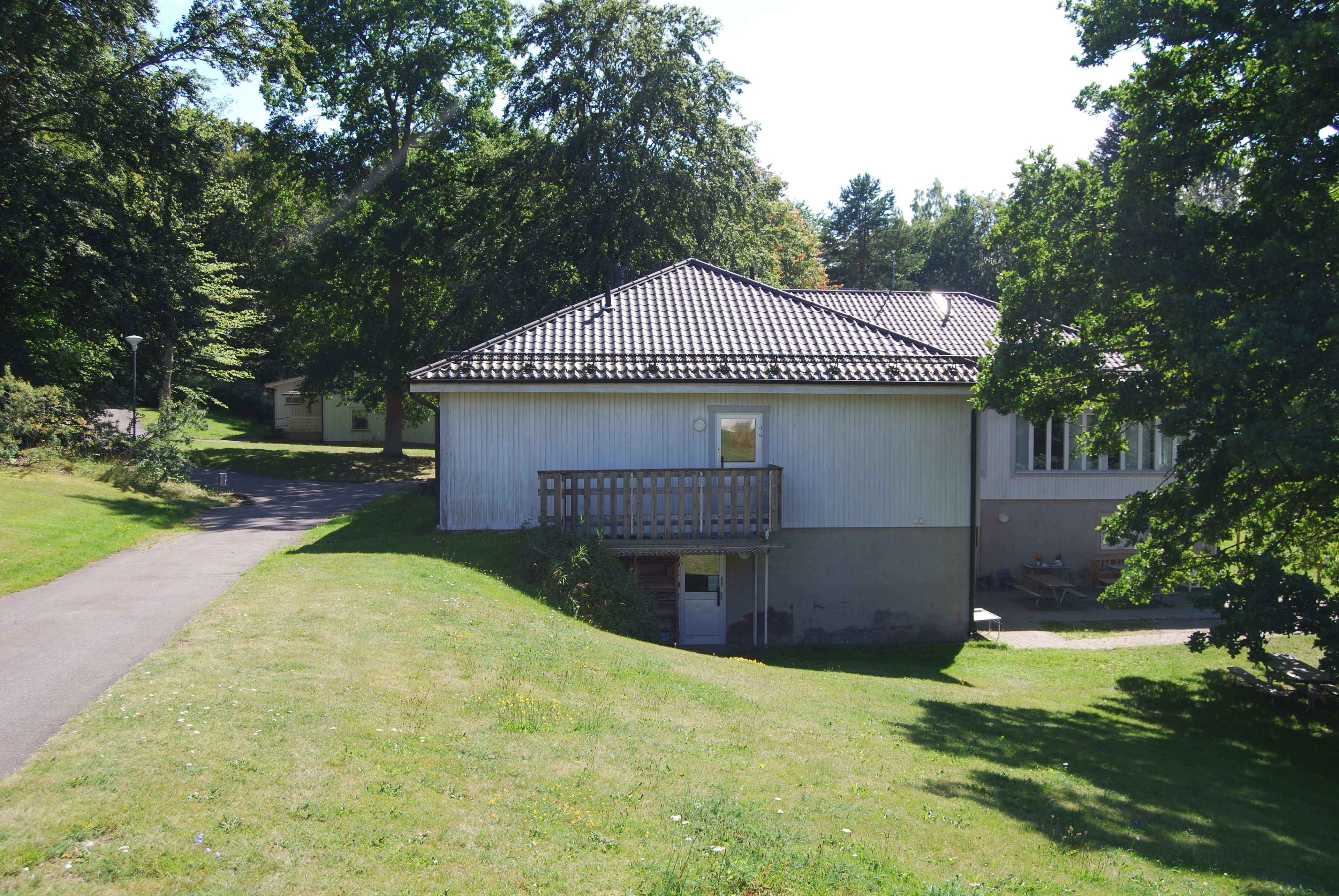 A single-story house with a tiled roof, a small porch, and a pathway leading to the entrance.