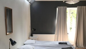 Une chambre à coucher avec un grand lit, une table de chevet, une lampe, un miroir et une fenêtre avec des rideaux.