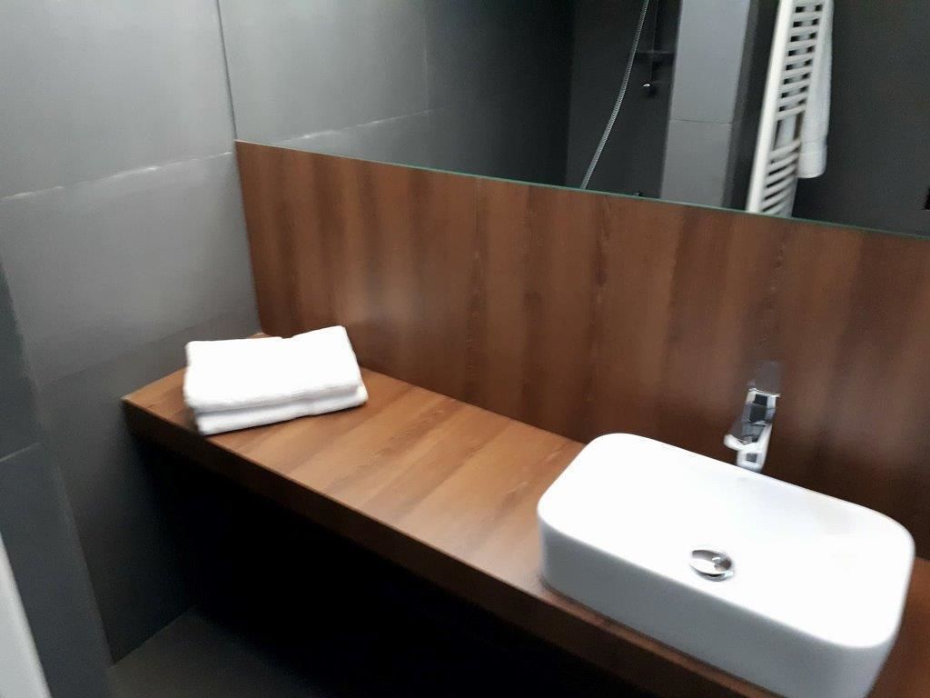 A bathroom with a wooden vanity, a white sink, and a towel.