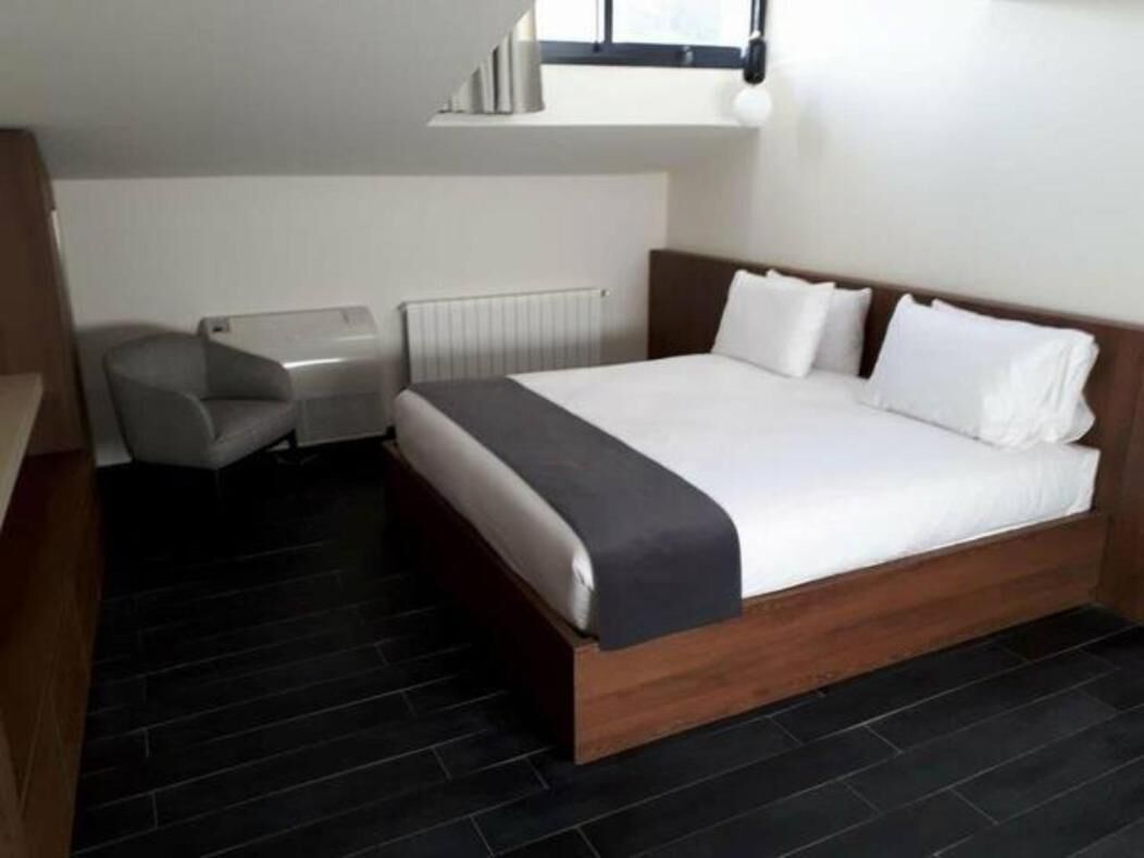 A modern hotel room with a large bed, a desk, and a chair.
