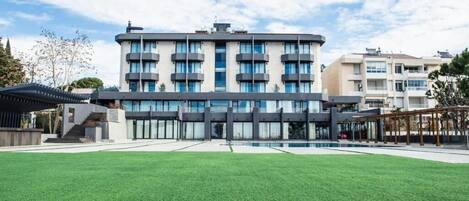 A modern multi-story building with a swimming pool in front.